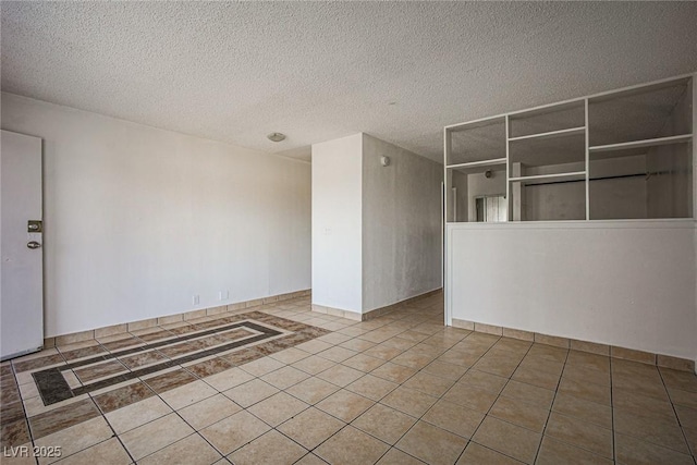 unfurnished room with a textured ceiling and tile patterned flooring