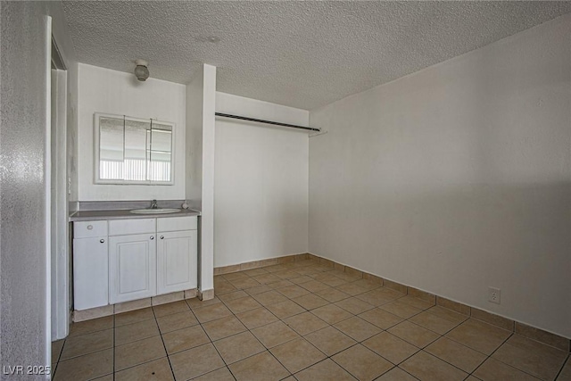 unfurnished room with a sink, a textured ceiling, and light tile patterned floors