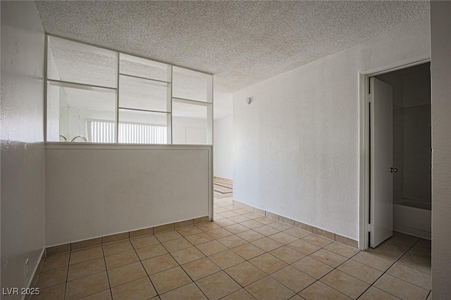 unfurnished room featuring tile patterned flooring, a textured wall, and a textured ceiling