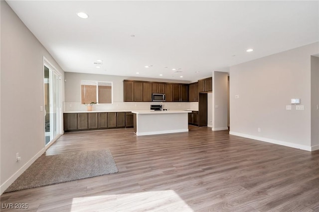 unfurnished living room with light wood-type flooring, baseboards, and recessed lighting