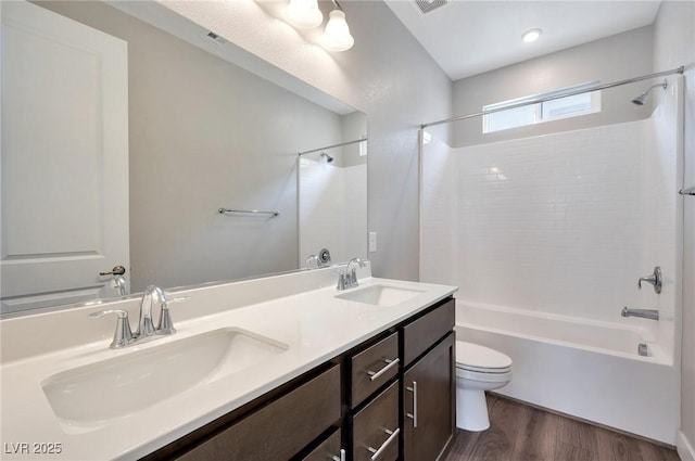 full bath with shower / bathtub combination, a sink, toilet, and wood finished floors