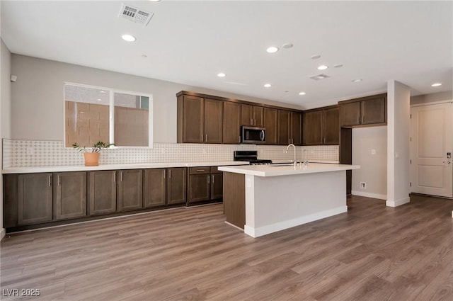 kitchen featuring light wood finished floors, appliances with stainless steel finishes, a sink, and visible vents