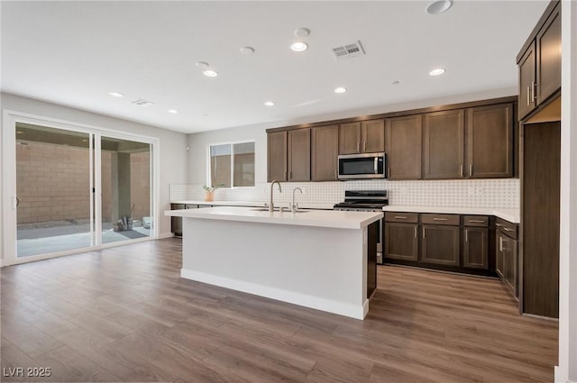 kitchen featuring appliances with stainless steel finishes, light countertops, a sink, and wood finished floors