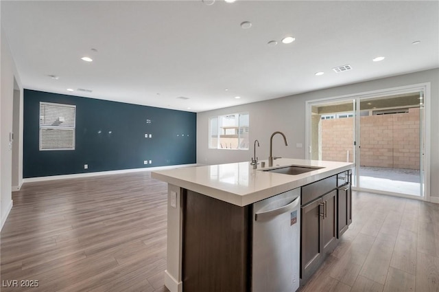 kitchen with a sink, light wood-style flooring, visible vents, and dishwasher