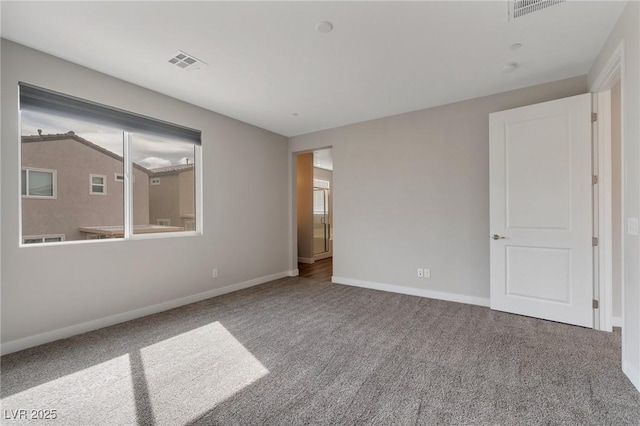 empty room featuring carpet floors, visible vents, and baseboards