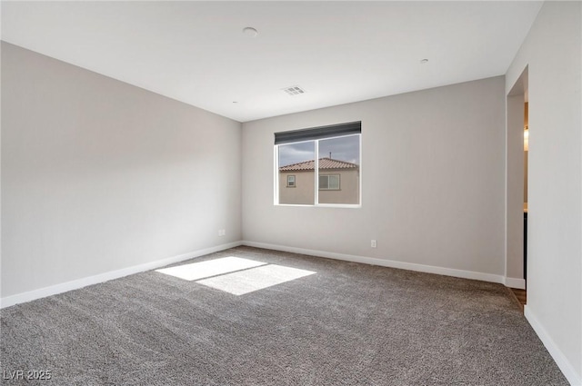 carpeted spare room featuring visible vents and baseboards