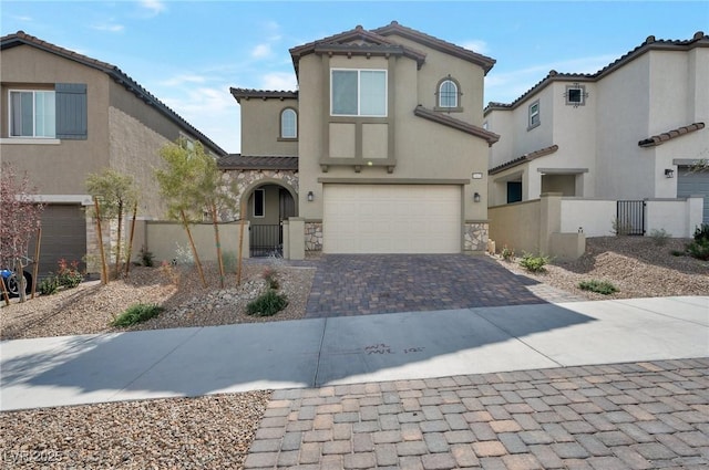 mediterranean / spanish-style house with stone siding, a gate, fence, and decorative driveway