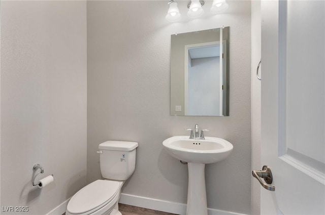 half bathroom with toilet and baseboards