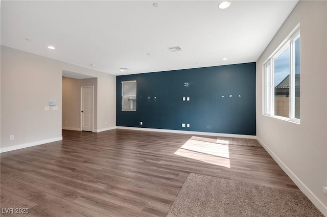 empty room featuring baseboards, visible vents, wood finished floors, and recessed lighting