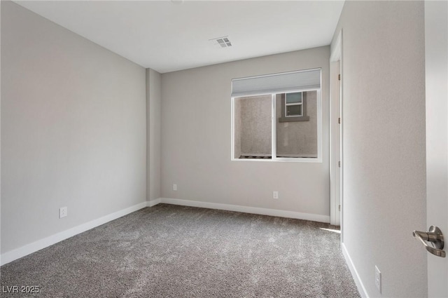 unfurnished room with carpet, visible vents, and baseboards