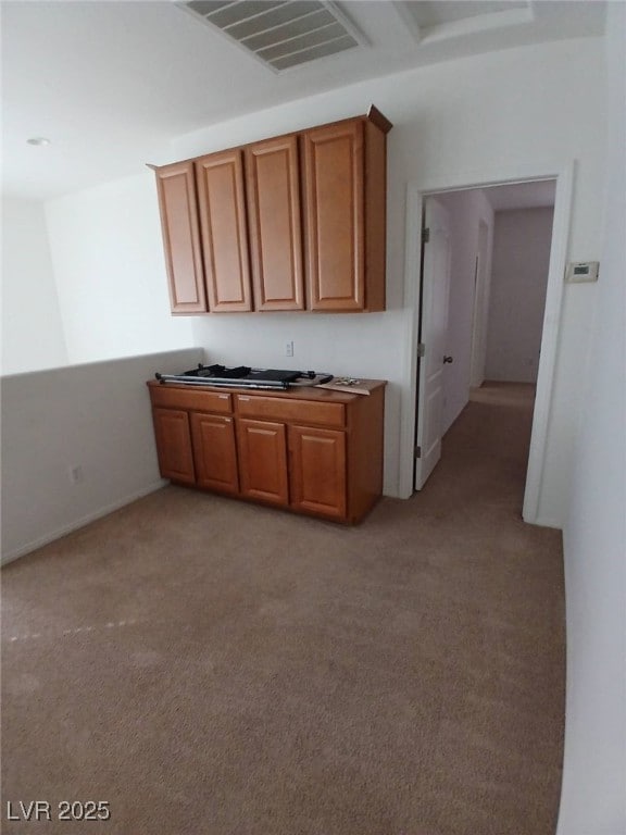 kitchen with visible vents, brown cabinetry, and light colored carpet