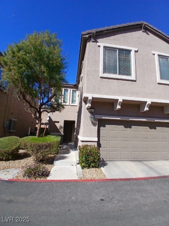 view of front of house with a garage, driveway, and stucco siding