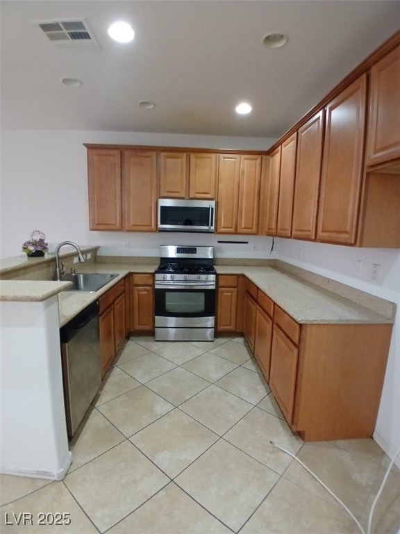 kitchen with a peninsula, a sink, visible vents, light countertops, and appliances with stainless steel finishes