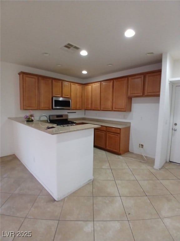 kitchen featuring appliances with stainless steel finishes, light countertops, brown cabinets, and visible vents