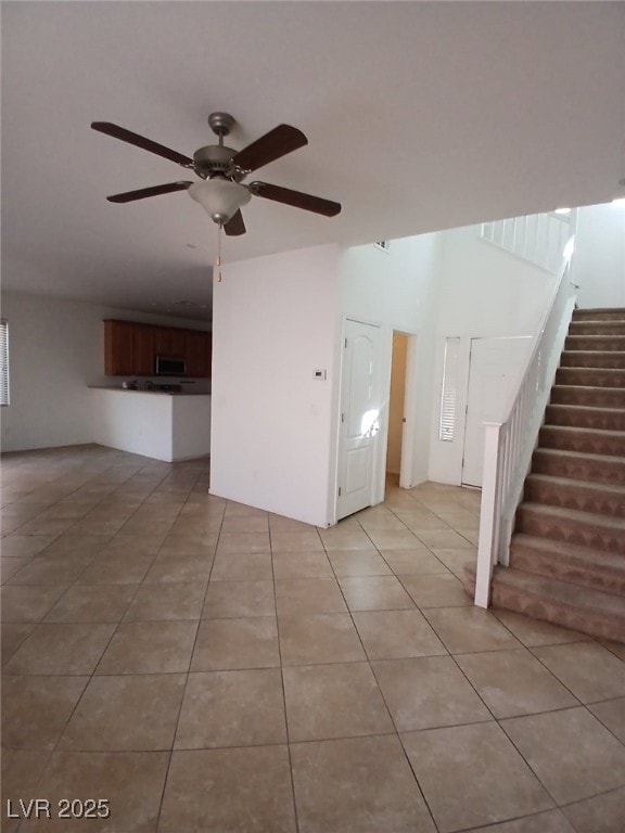 unfurnished living room featuring stairs, a ceiling fan, and light tile patterned floors