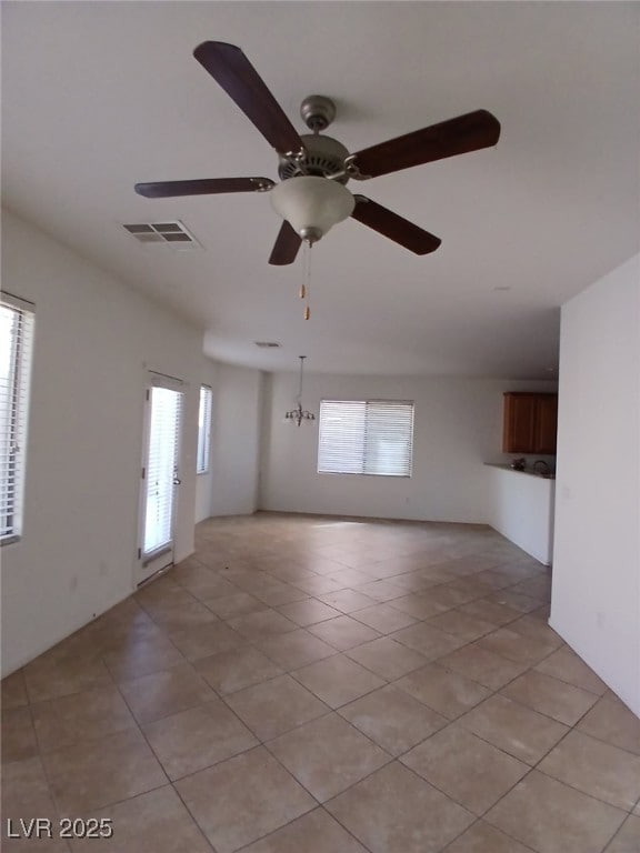 empty room featuring ceiling fan, light tile patterned flooring, and visible vents