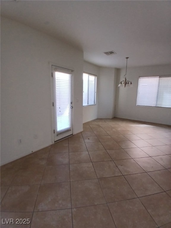 unfurnished dining area featuring visible vents, an inviting chandelier, and tile patterned floors