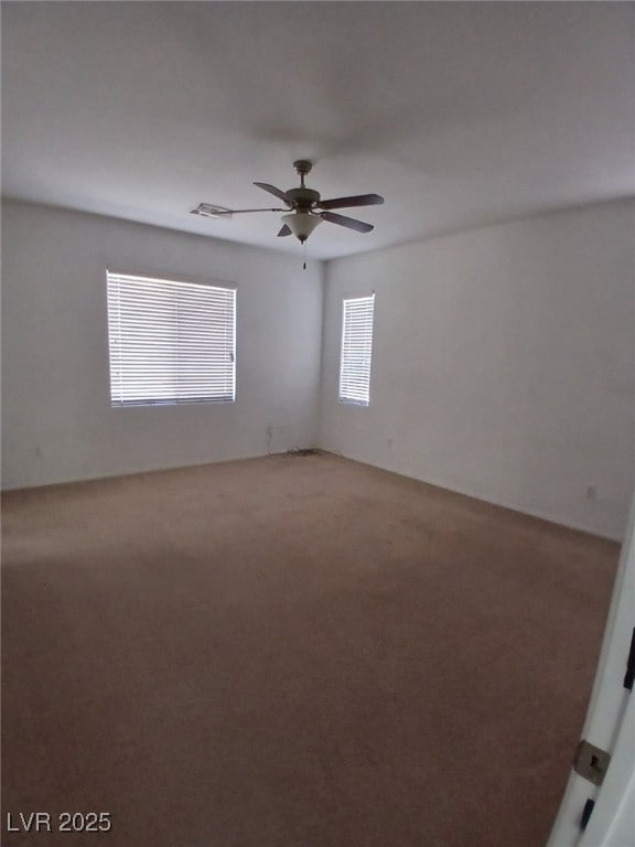 carpeted empty room featuring visible vents and ceiling fan