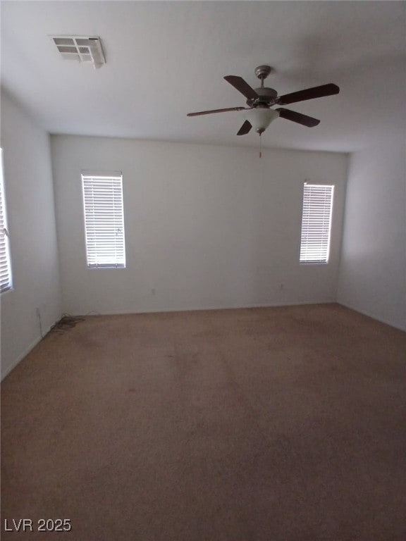 unfurnished room featuring light colored carpet, a wealth of natural light, visible vents, and a ceiling fan