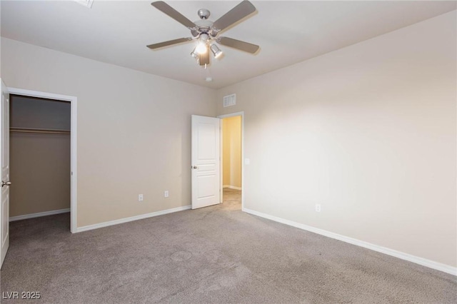 unfurnished bedroom featuring baseboards, visible vents, a walk in closet, carpet floors, and a closet