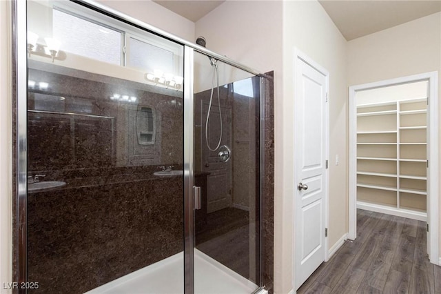 full bathroom with a spacious closet, a stall shower, and wood finished floors