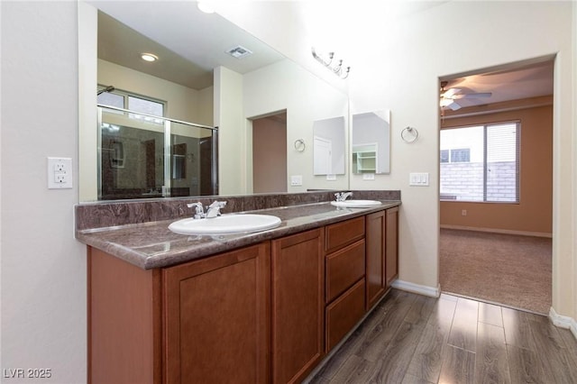 full bathroom with wood finished floors, visible vents, a sink, and double vanity