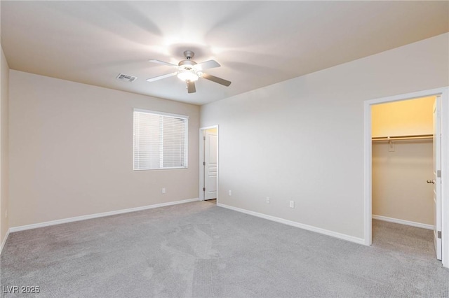 unfurnished bedroom featuring ceiling fan, light carpet, visible vents, baseboards, and a spacious closet