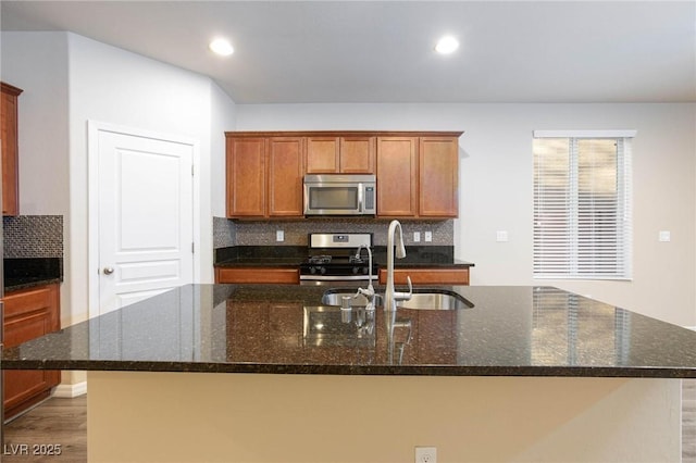 kitchen featuring a center island with sink, appliances with stainless steel finishes, backsplash, and a sink