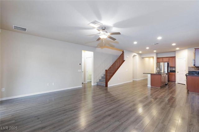 unfurnished living room with stairs, visible vents, and dark wood finished floors