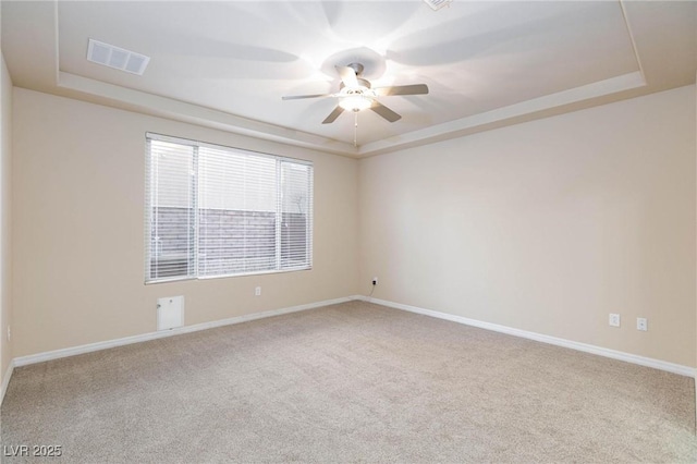 spare room featuring visible vents, baseboards, ceiling fan, a tray ceiling, and carpet floors