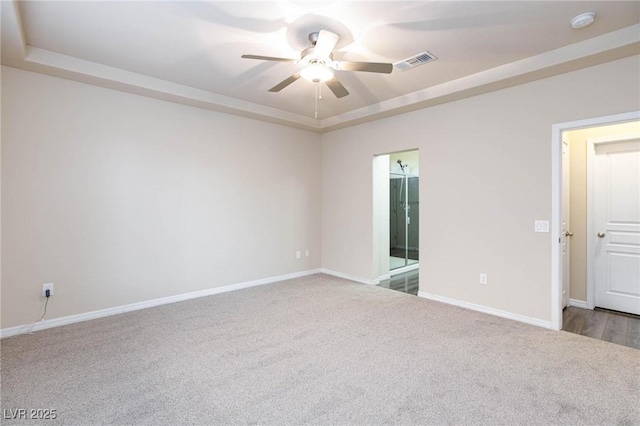 spare room featuring carpet, a raised ceiling, and visible vents