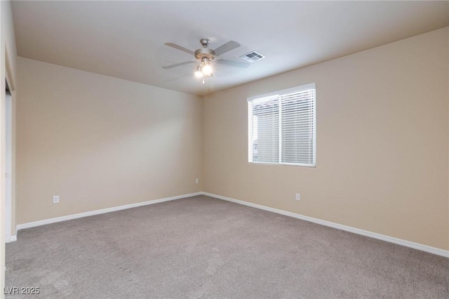 carpeted spare room featuring baseboards, visible vents, and a ceiling fan