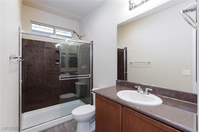 bathroom featuring a stall shower, vanity, toilet, and wood finished floors