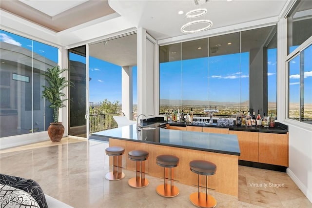 bar with a healthy amount of sunlight, floor to ceiling windows, a sink, and decorative light fixtures