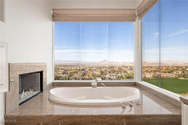 bathroom with a tile fireplace, a mountain view, and a tub