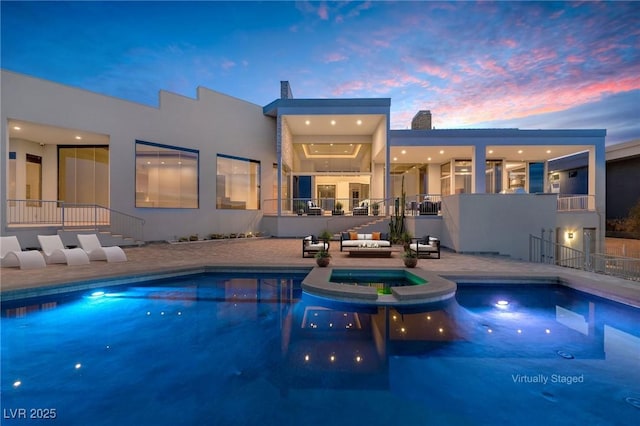 pool at dusk with a patio area and a pool with connected hot tub