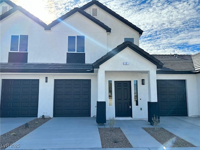 view of front of property featuring a tile roof, driveway, and stucco siding