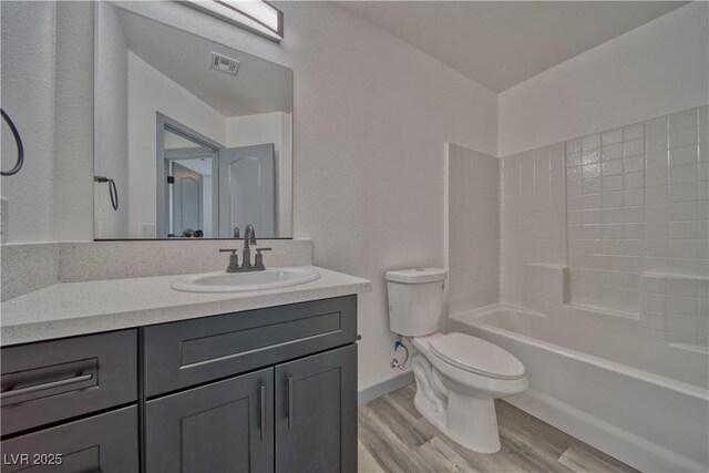 bathroom featuring visible vents, toilet, shower / tub combination, wood finished floors, and vanity