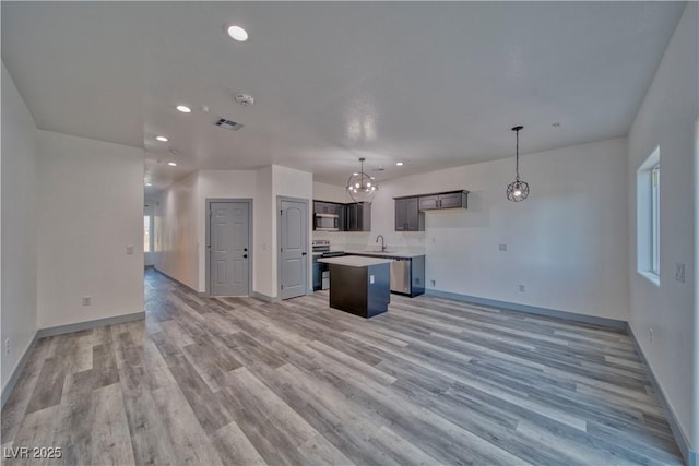 kitchen featuring appliances with stainless steel finishes, light wood-type flooring, open floor plan, and a kitchen island
