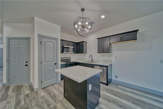 kitchen featuring light wood finished floors, stainless steel appliances, light countertops, an inviting chandelier, and a sink