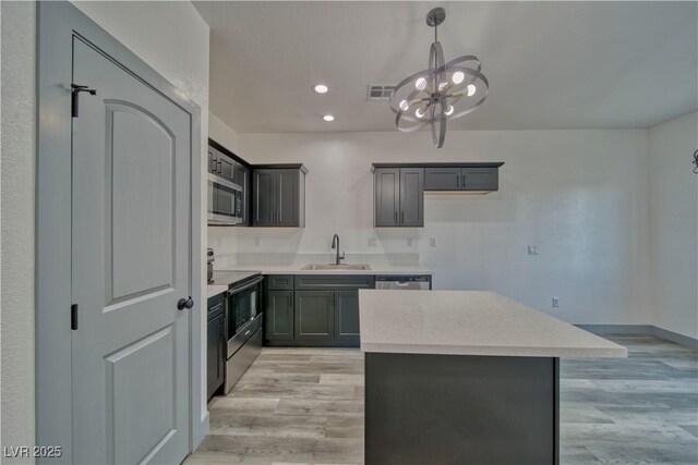 kitchen featuring range with electric stovetop, stainless steel microwave, visible vents, a sink, and light wood-type flooring