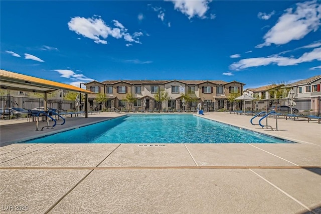 pool with a patio area, a residential view, and fence