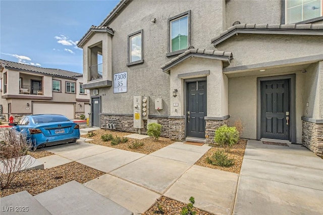 doorway to property featuring stucco siding, stone siding, and a tile roof