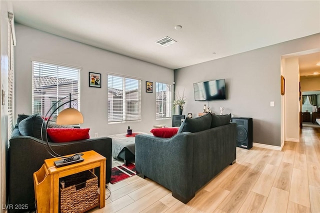 living room featuring visible vents, baseboards, and light wood-style flooring