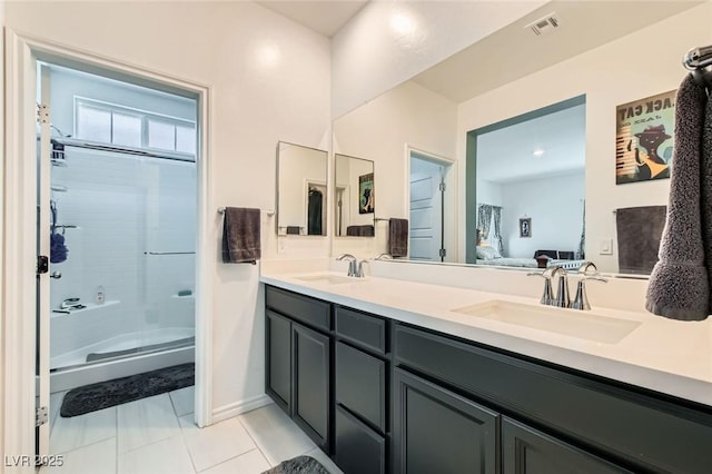 full bath with double vanity, tile patterned floors, a shower with door, and a sink