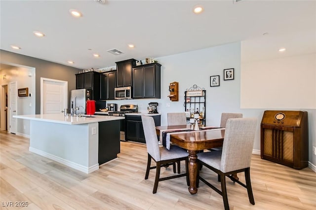 kitchen featuring visible vents, light wood-type flooring, an island with sink, recessed lighting, and appliances with stainless steel finishes