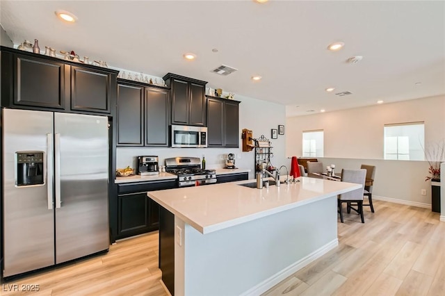 kitchen featuring light wood-style flooring, appliances with stainless steel finishes, light countertops, and a sink