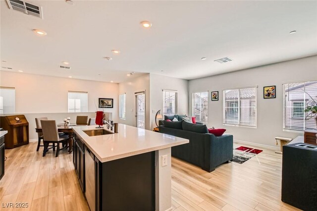 kitchen featuring light countertops, visible vents, open floor plan, and a sink