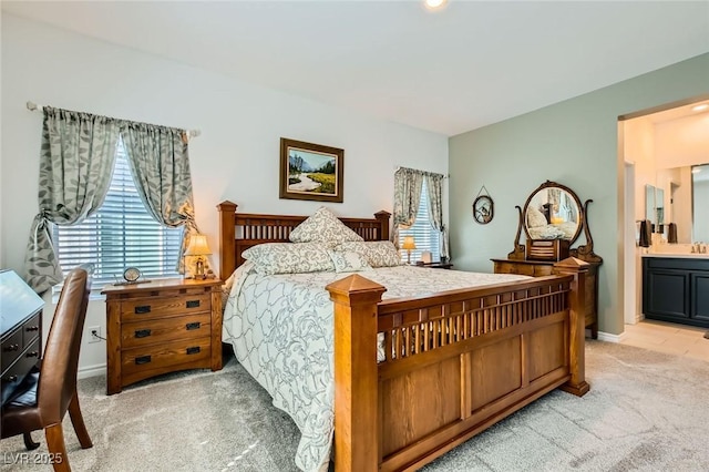 bedroom with baseboards, light carpet, and ensuite bath