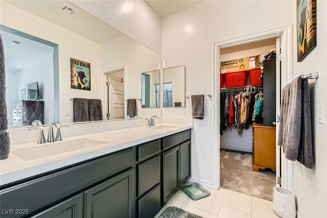 bathroom featuring a sink, a walk in closet, double vanity, and tile patterned flooring